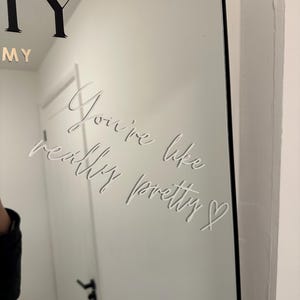 May include: A rectangular mirror with a black frame. The mirror has the words "You're like really pretty" etched into the surface in a cursive font. The word "MY" is visible at the top.