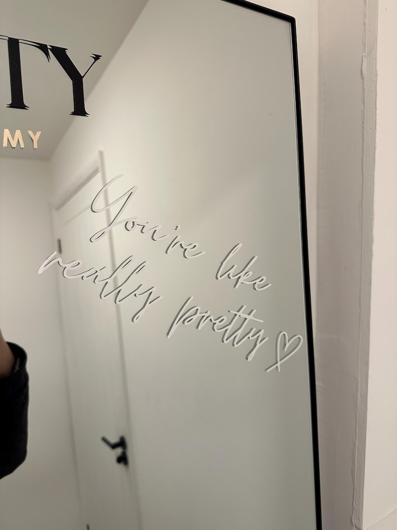 May include: A rectangular mirror with a black frame. The mirror has the words "You're like really pretty" etched into the surface in a cursive font. The word "MY" is visible at the top.