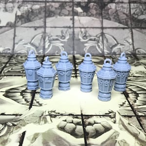 May include: Six small, gray, metal lanterns with numbers on them. The lanterns are arranged in a row on a gray tiled surface.