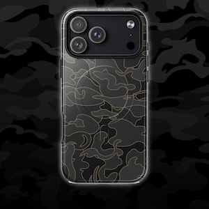 May include: A clear phone case with a black and gold camouflage pattern. The case has a camera cutout with three lenses and a flash. The word "CAMO" is written in white letters at the bottom of the image.