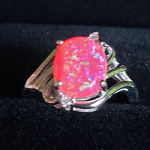 May include: A silver ring with a pink opal gemstone set in a swirl design.