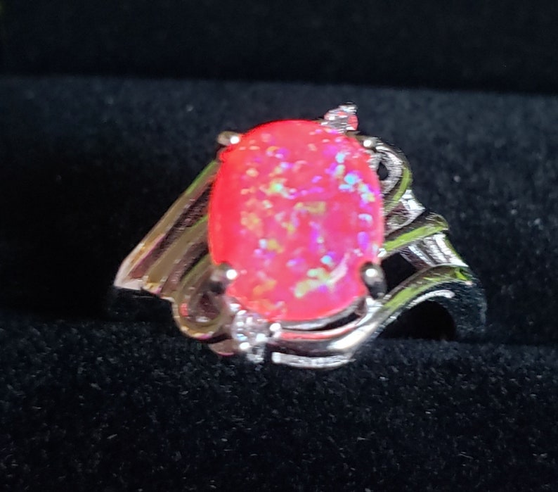 May include: A silver ring with a pink opal gemstone set in a swirl design.