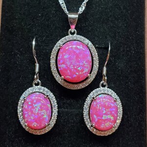 Puede incluir: Un conjunto de collar y pendientes de &oacute;palo rosa con una cadena de plata y piedras de forma ovalada rodeadas de circonitas c&uacute;bicas transparentes.
