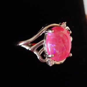May include: A silver ring with a pink opal gemstone and small clear stones set in the band.