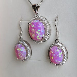 May include: A pink opal necklace and earrings set with a silver chain and a silver setting with small clear stones around the opal.