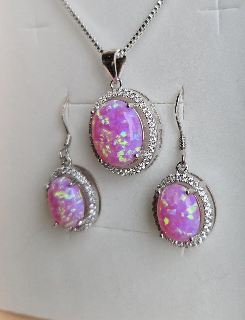 May include: A pink opal necklace and earrings set with a silver chain and a silver setting with small clear stones around the opal.