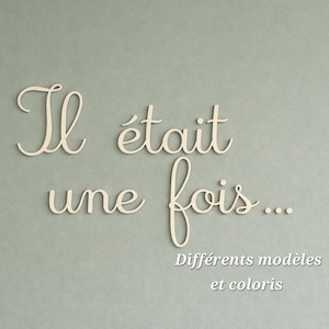 Peut inclure: Une enseigne murale en bois clair présentant le texte en cursive "Il était une fois..." suivi du texte plus petit "Différents modèles et coloris" positionné sous la phrase principale, le tout dans une police d'écriture élégante.