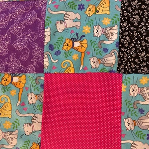 Puede incluir: Un edredón de retazos con varios patrones de tela. El edredón incluye cuadrados de tela floral púrpura, estampado de gato turquesa, floral en blanco y negro y lunares rosas. El estampado de gato presenta gatos de dibujos animados.