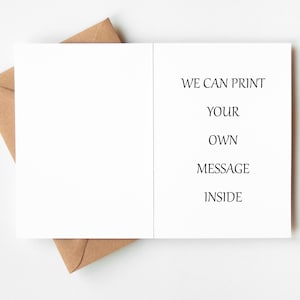 May include: A blank white greeting card with the text "WE CAN PRINT YOUR OWN MESSAGE INSIDE" is displayed open, resting on a brown envelope. The card and envelope are on a white surface. The card is ready for a custom message.