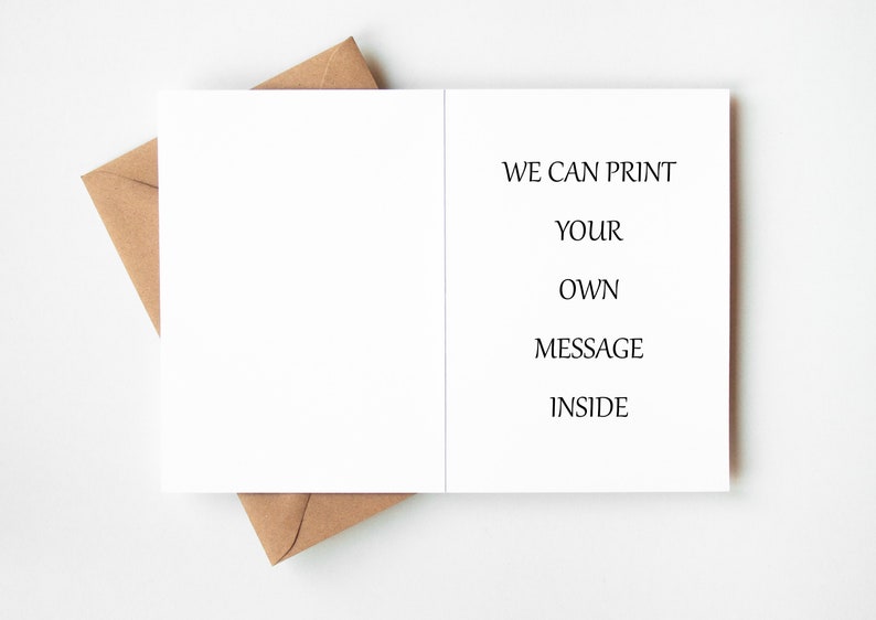 May include: A blank white greeting card with the text "WE CAN PRINT YOUR OWN MESSAGE INSIDE" is displayed open, resting on a brown envelope. The card and envelope are on a white surface. The card is ready for a custom message.