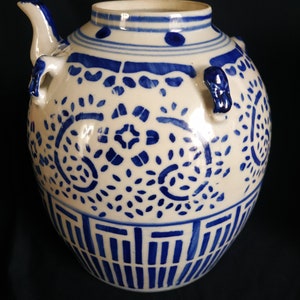 May include: A white ceramic teapot with blue and white floral designs. The teapot has a spout and two handles.