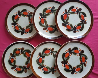 May include: Six ceramic plates with a white background and a brown and orange floral design. The plates have a raised rim and a slightly scalloped edge.