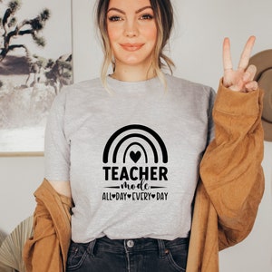 May include: A grey t-shirt with a rainbow and the text "Teacher mode - all day every day" printed on it.