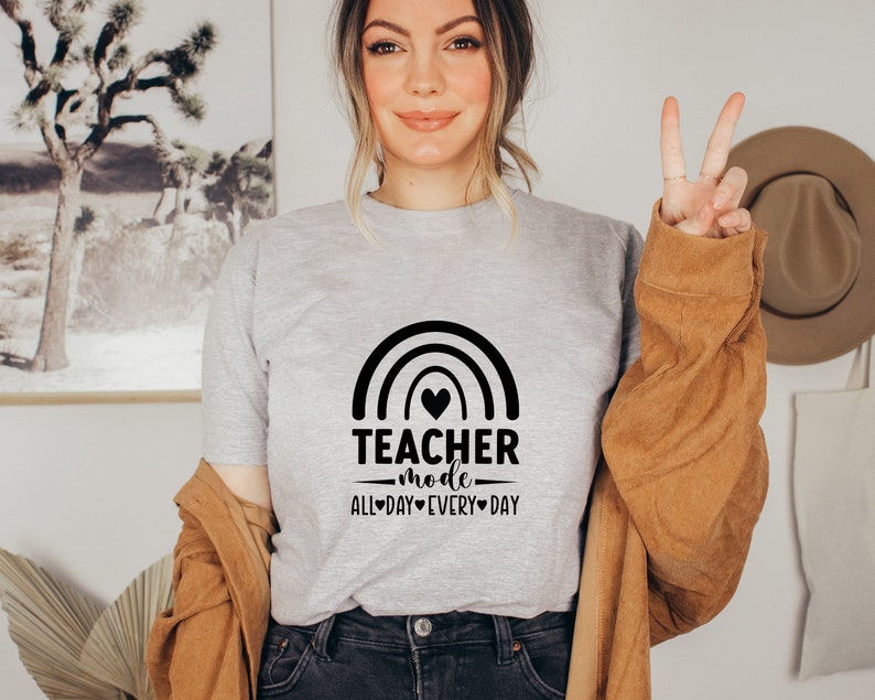 May include: A grey t-shirt with a rainbow and the text "Teacher mode - all day every day" printed on it.