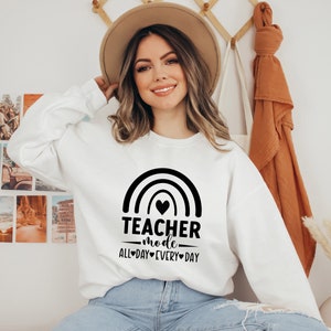 May include: White sweatshirt with a black rainbow graphic and the text "Teacher mode all-day every-day".