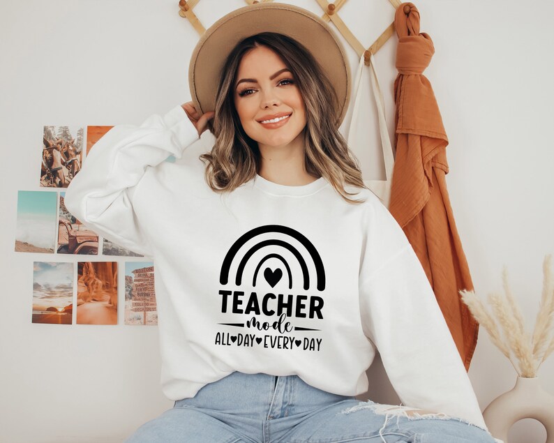 May include: White sweatshirt with a black rainbow graphic and the text "Teacher mode all-day every-day".