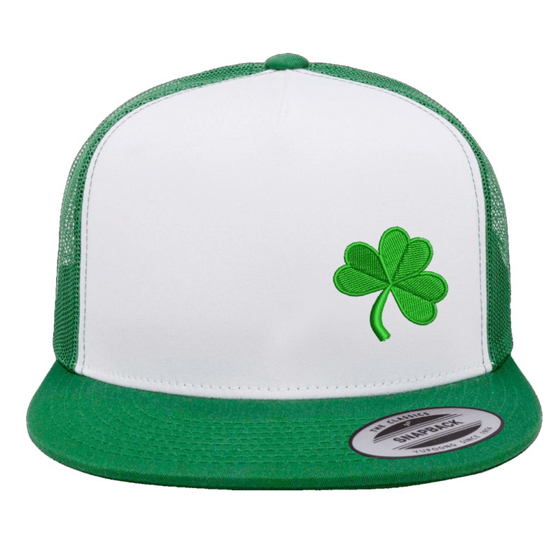 May include: White and green trucker hat with a green shamrock embroidered on the front. The hat has a mesh back and a green brim.