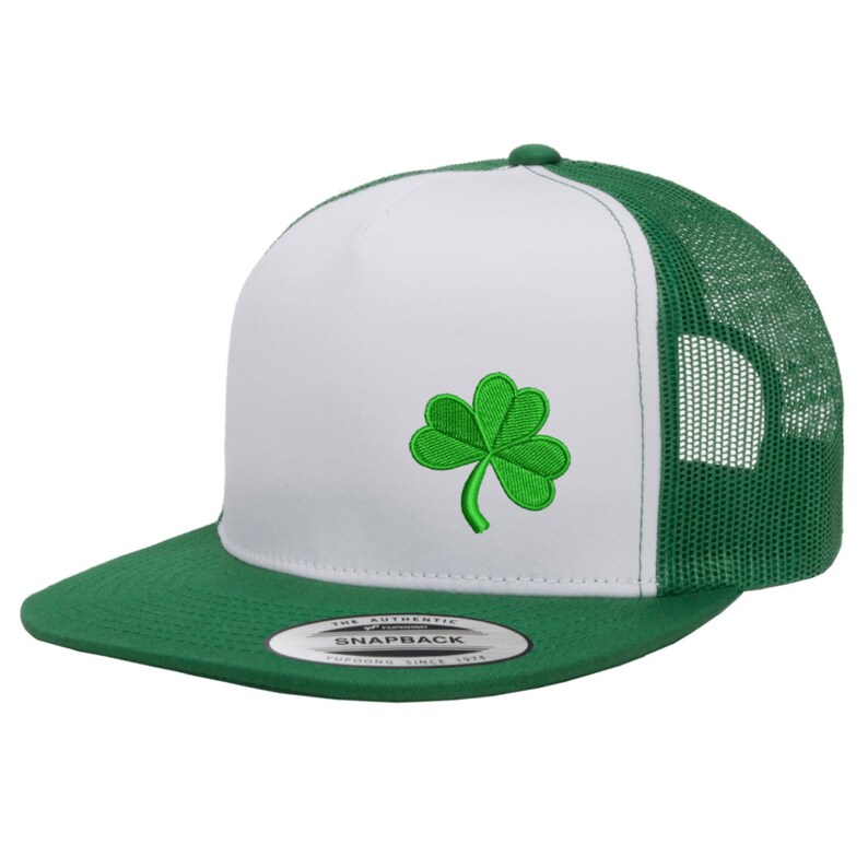 May include: White and green trucker hat with a green shamrock embroidered on the front. The hat has a mesh back and a green brim.