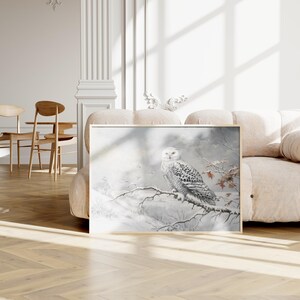 May include: A snowy owl perched on a branch in a wintry scene. The owl is white with black markings and has yellow eyes. The background is a soft, muted grey with hints of blue and white.