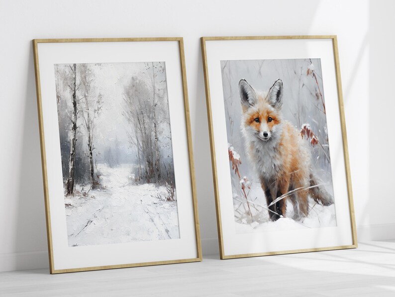May include: Two framed prints, one depicting a snowy forest path and the other featuring a red fox standing in a snowy woodland. Both prints have a white background and a light wood frame.