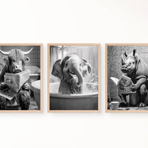 May include: Set of three framed black and white prints. Each print features an animal in a bathroom setting: a Highland cow reading a newspaper in a bathtub, an elephant in a tub, and a rhino on a toilet reading a newspaper.
