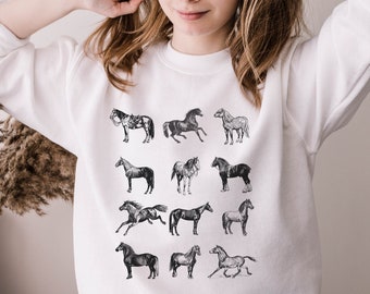 May include: White sweatshirt with a black and white graphic print of horses. The horses are in various poses and are arranged in a grid pattern.