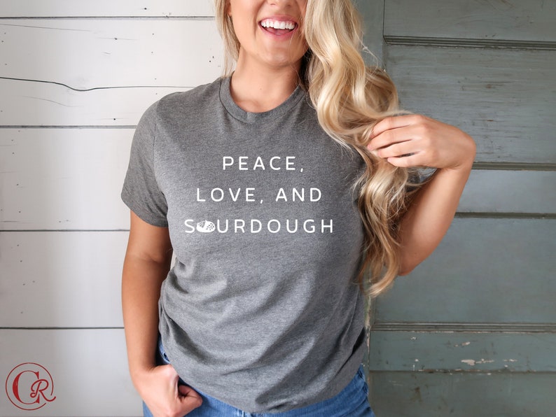 Pode incluir: Uma camiseta cinza com o texto "Peace, Love, and Sourdough" impresso em branco.