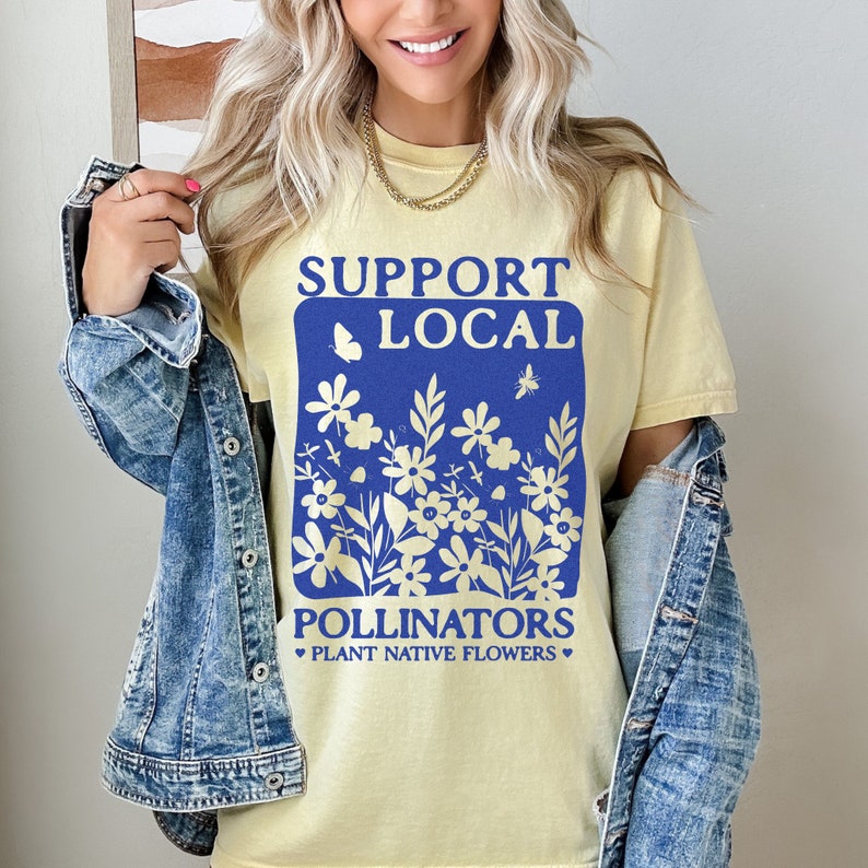 May include: A yellow t-shirt with a blue graphic that says "Support Local Pollinators Plant Native Flowers". The graphic features a butterfly, a bee, and a floral design.