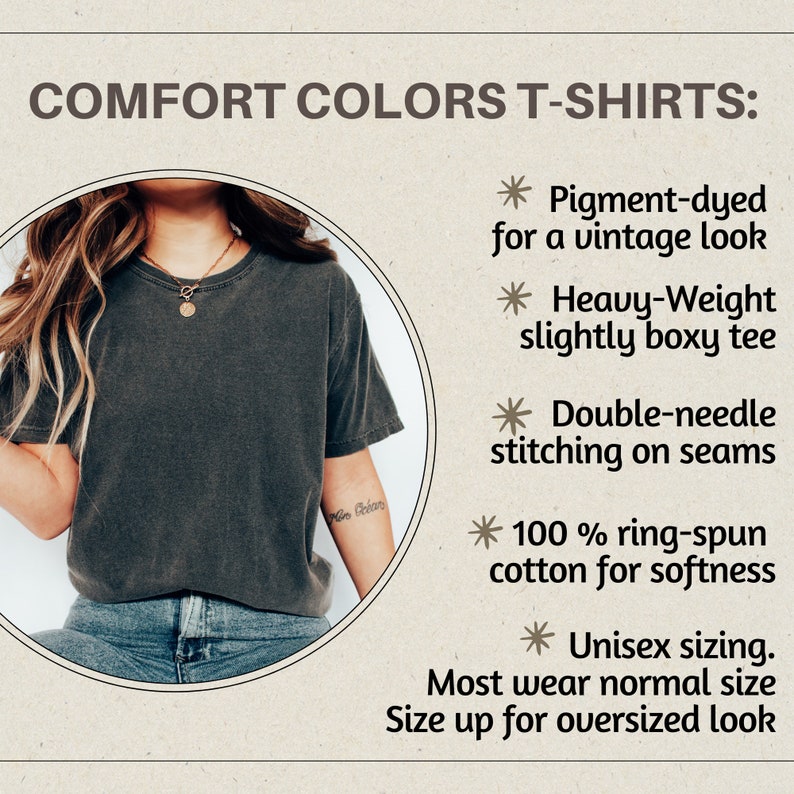 May include: A close-up of a person wearing a dark gray, pigment-dyed t-shirt with a slightly boxy fit. The t-shirt is made of 100% ring-spun cotton for softness and features double-needle stitching on the seams. The text "More Better" is visible on the person's arm.