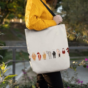 May include: A white tote bag with a black strap and a row of colourful horses printed on the front. The horses are facing away from the viewer.