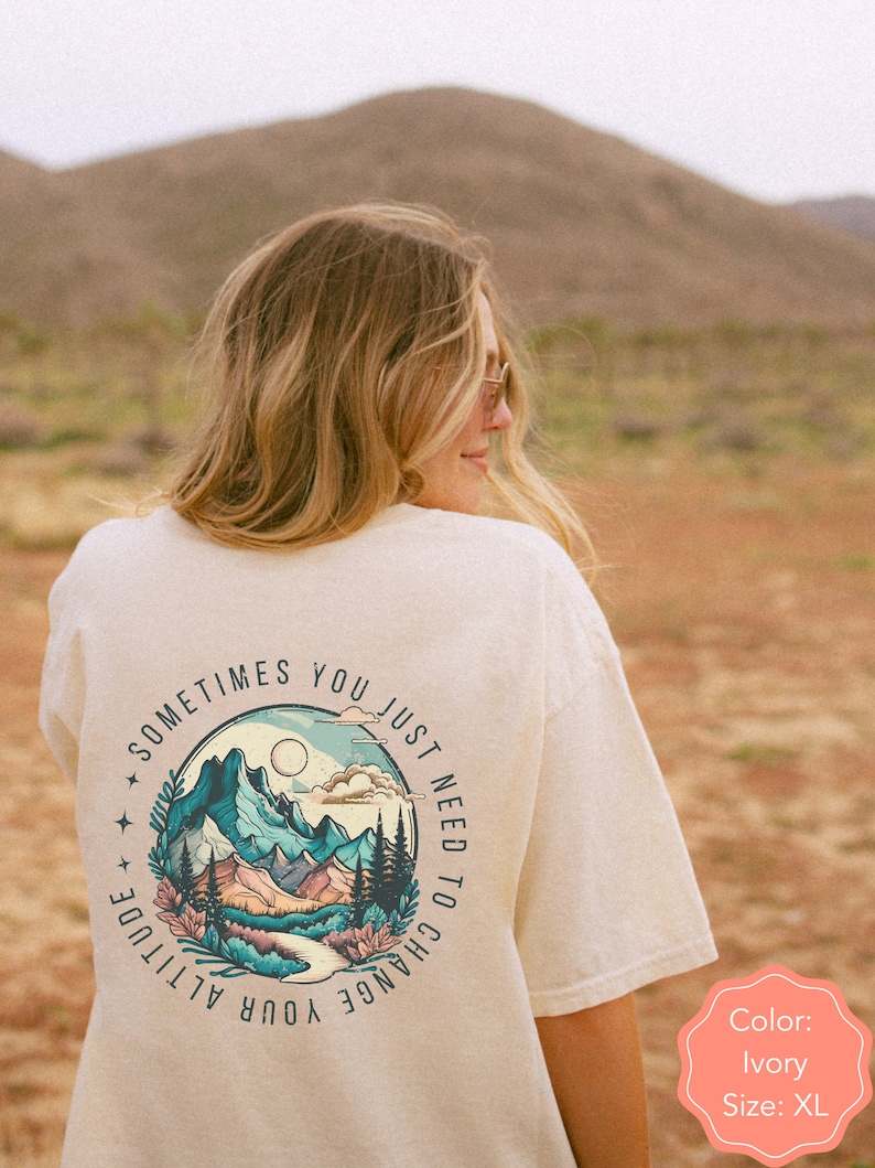 May include: Ivory t-shirt with a graphic of mountains and the text "Sometimes you just need to change your altitude".
