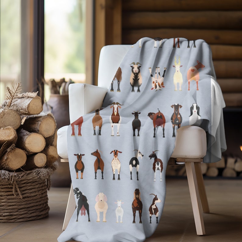 May include: A soft blue fleece throw blanket with a repeating pattern of goats in various poses. The goats are brown, white, and black with different markings. The blanket is draped over a white armchair.