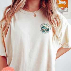 May include: Ivory t-shirt with a graphic of mountains and a river with the text "Sometimes you just need to change your attitude".