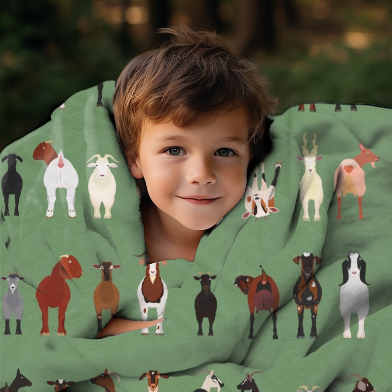 May include: A child is wrapped in a green fleece blanket featuring a repeating pattern of goats in various colours and poses. The blanket is soft and cosy, ideal for snuggling up on the sofa.