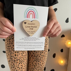 Pu&ograve; includere: Un portafortuna di legno a forma di cuore con il testo "Amelia's Little Pocket Hug" e "From Mummy & Daddy". Il cuore &egrave; attaccato a una carta con un design arcobaleno e il testo "Tutti hanno un primo giorno Quando si sentono spaventati e soli Ma ti promettiamo che ti divertirai molto E non sarai solo. Avrai molte nuove avventure e momenti emozionanti da vivere E farai molti nuovi amici e ricordi indimenticabili. Non dimenticare che saremo insieme non appena la giornata finir&agrave;. Quindi sii coraggioso, piccolo, non hai niente da temere Ti vogliamo molto bene e siamo orgogliosi della piccola persona coraggiosa che sei diventato."