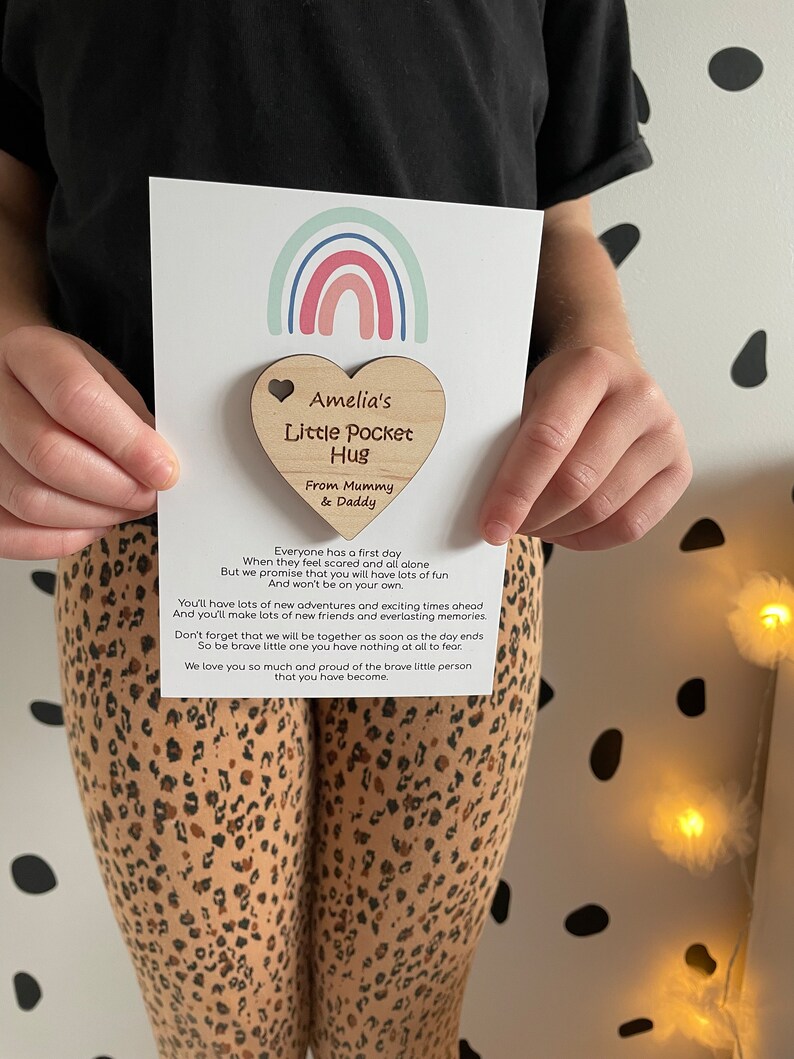Pu&ograve; includere: Un portafortuna di legno a forma di cuore con il testo "Amelia's Little Pocket Hug" e "From Mummy & Daddy". Il cuore &egrave; attaccato a una carta con un design arcobaleno e il testo "Tutti hanno un primo giorno Quando si sentono spaventati e soli Ma ti promettiamo che ti divertirai molto E non sarai solo. Avrai molte nuove avventure e momenti emozionanti da vivere E farai molti nuovi amici e ricordi indimenticabili. Non dimenticare che saremo insieme non appena la giornata finir&agrave;. Quindi sii coraggioso, piccolo, non hai niente da temere Ti vogliamo molto bene e siamo orgogliosi della piccola persona coraggiosa che sei diventato."