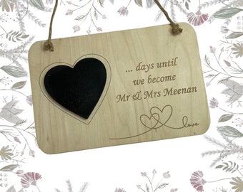 May include: Wooden sign with a chalkboard heart and the text "... days until we become Mr & Mrs Meenan love".