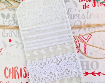 May include: A white fabric gift tag with a white lace trim and a gray and white striped pattern. The tag is tied with a green and white twine and has the text "www.mittsyrum.com @sweettallojh" printed on it.