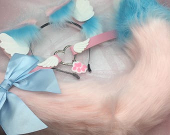 Pode incluir: Um conjunto de cosplay em tons pastel com uma tiara com orelhas fofas azuis e rosa, uma cauda a condizer e uma gargantilha rosa com um pingente em forma de coração e uma pegada de pata. Um grande laço azul de cetim adiciona um toque decorativo.