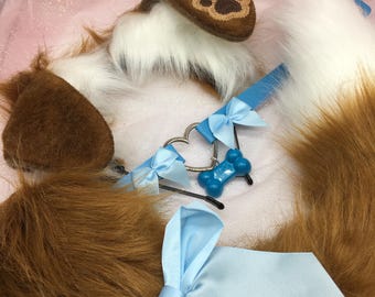 Peut inclure: Un serre-tête avec des oreilles de chien en fourrure marron et blanche avec un motif de patte, un collier bleu clair avec un charme en forme de cœur et un pendentif en forme d'os, et un nœud bleu clair. La queue est marron et blanche.