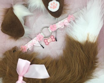Peut inclure: Ensemble de cosplay sur le thème du chien, marron et blanc. Il comprend des oreilles, une queue et un collier. Les oreilles ont une empreinte de patte rose, le collier des nœuds et des fleurs roses. La queue est touffue et le collier a un charme en forme d'os rose.