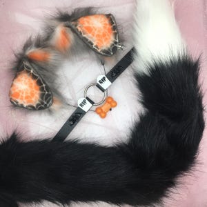 May include: A Halloween-themed cosplay set featuring a black and white faux fur tail, matching cat ears with orange and black accents, and a black collar with a bone charm and RIP tags.