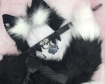May include: Black and white faux fur tail with a black choker and a paw print charm. The tail is fluffy and soft, and the choker is adjustable.