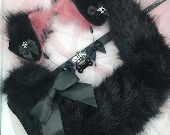 May include: A black faux fur tail, ear cuffs, and collar set. The set includes a fluffy tail, ear cuffs with black bows and paw print charms, and a collar with a bone-shaped charm. The ears have pink fur accents.