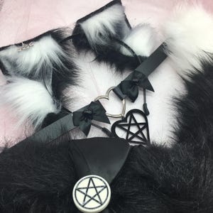 May include: Black and white faux fur collar with a black choker necklace featuring a silver heart charm and a black pentagram charm.