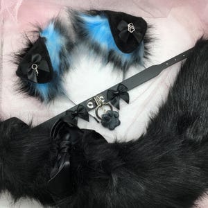May include: A black faux fur tail with a black choker and two blue and black faux fur ears. The choker has a silver charm with a paw print.