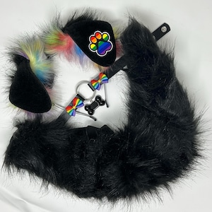 May include: A set of black faux fur animal ears with rainbow-colored inner fur, a black collar featuring a silver O-ring, two small rainbow-striped bows, and a black bone-shaped tag, alongside a long, black faux fur tail with a snap closure.