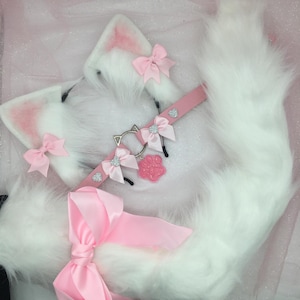 May include: White faux fur cat ears and tail with pink bows and a pink choker with a silver paw charm.