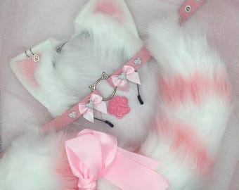 Op de afbeelding: Roze en witte nep bont kattenoren, staart en strik met een roze choker met een zilveren pootbedel en strass.