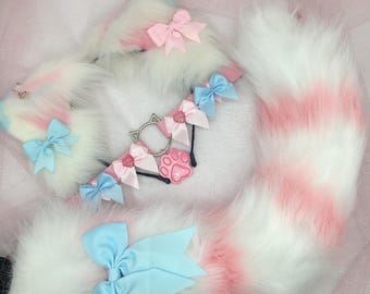 May include: A pink and white fluffy cat tail with a blue bow, a pink and white fluffy cat ear headband with a pink bow, and a pink and white cat collar with a paw charm.